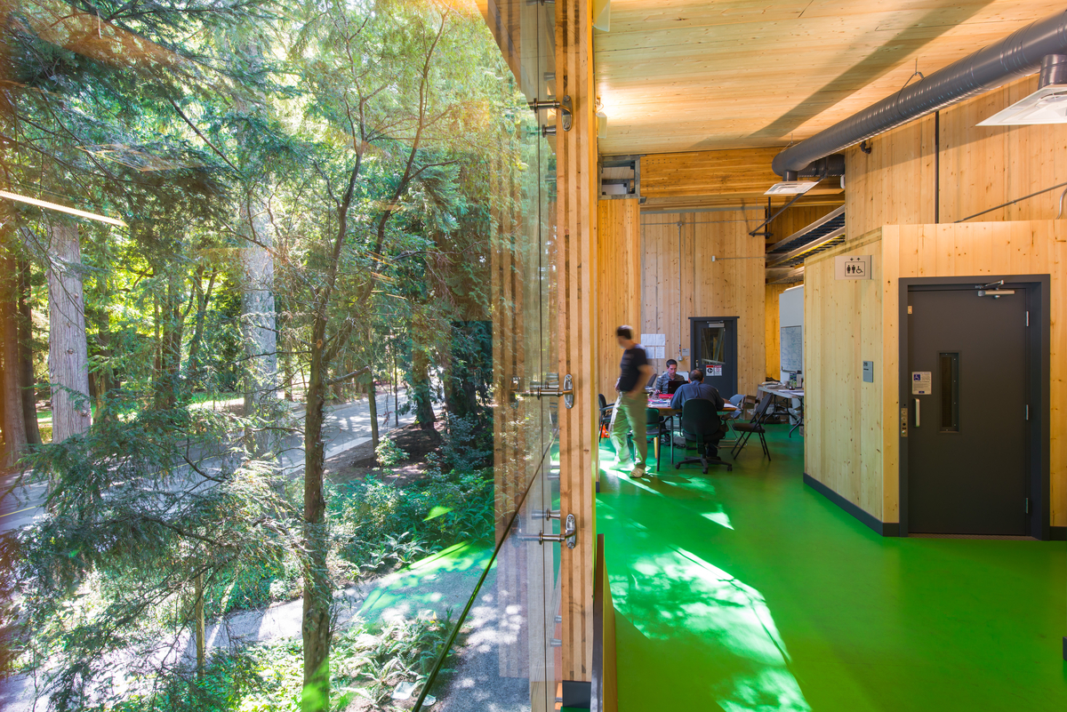 UBC生物能源研究和演示设施的室内白天景观，展示了一群工程师坐在桌子旁，周围是木镶板墙和天花板，由大型胶合木(胶合木)梁和柱支撑