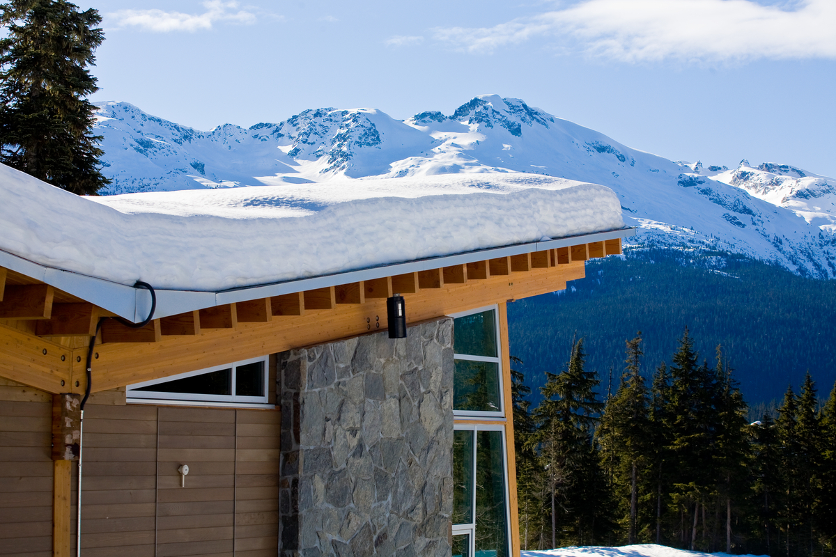 户外阳光明媚的视图显示的角落混合木建筑与它的胶水层积木材(胶合)梁支持木制屋顶结构,雪之上,远处群山