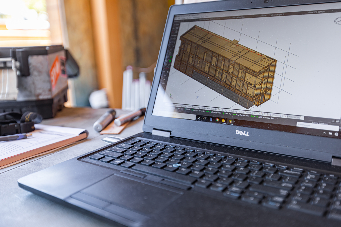 打开笔记本电脑，在屏幕上显示一个木制建筑的设计方案