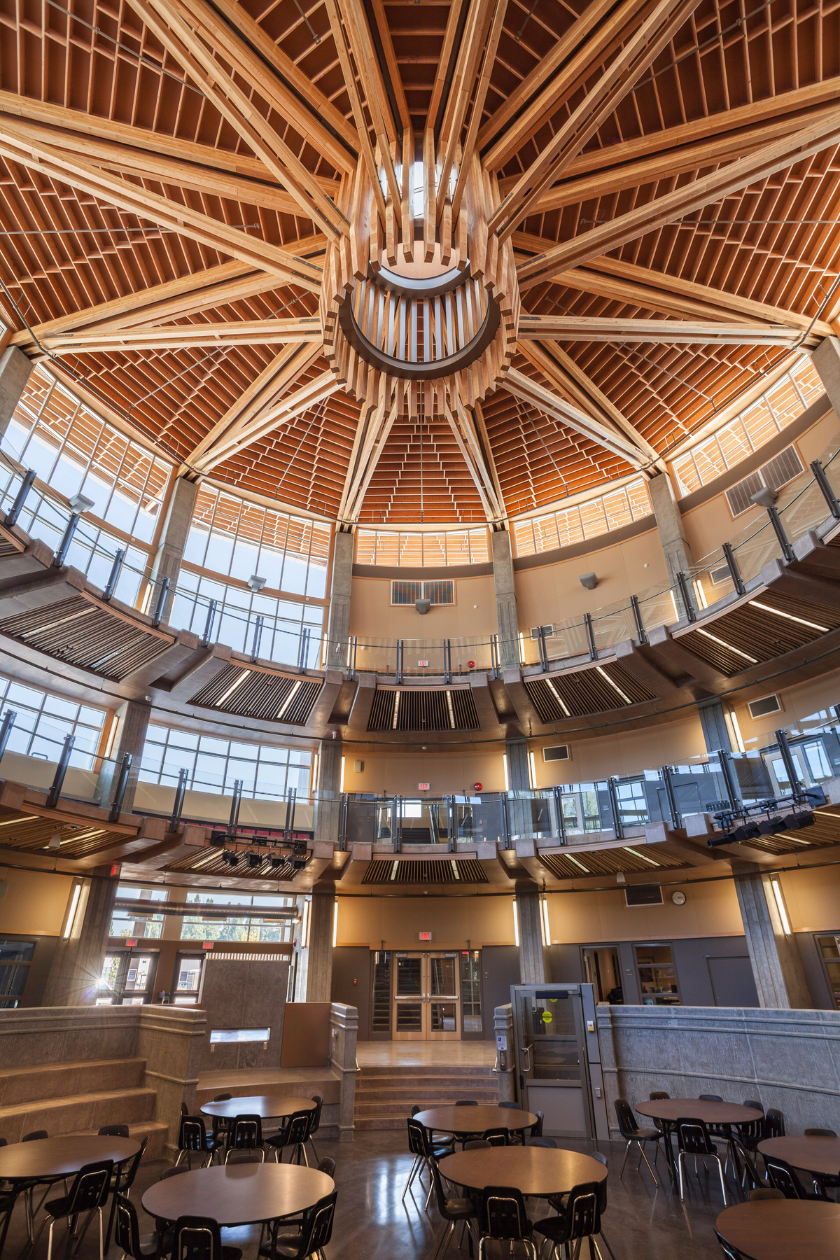 胶合木(胶合木)、镶板、胶合板和实锯重型木材组合在一起，创造了同心圆和圆形阳台，这是Abbotsford高级中学天花板的室内图像