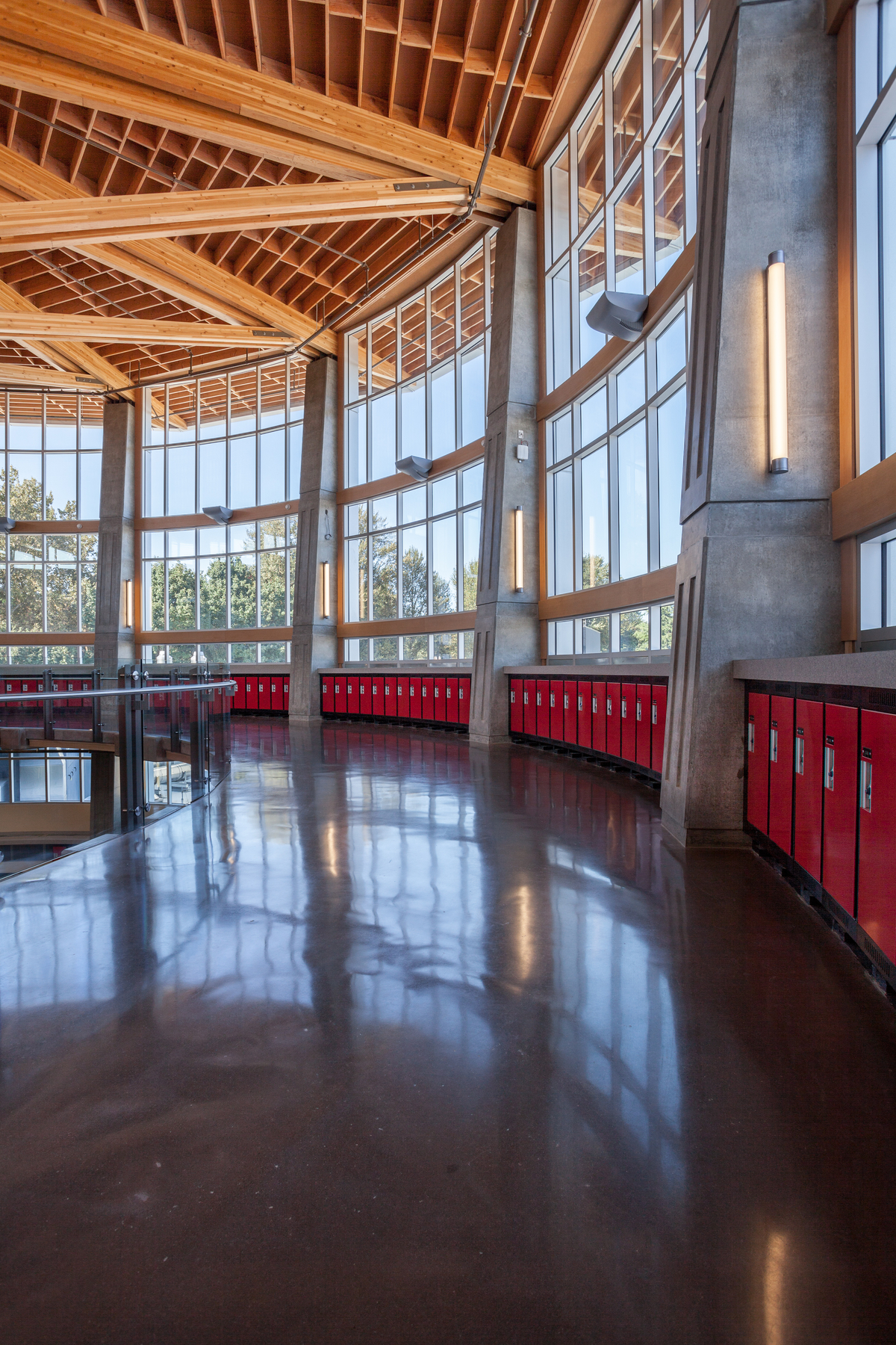 Abbotsford高级中学的室内阳光白天视图，展示了混凝土支撑柱结合使用钢支架和胶合木(胶合木)梁的接缝