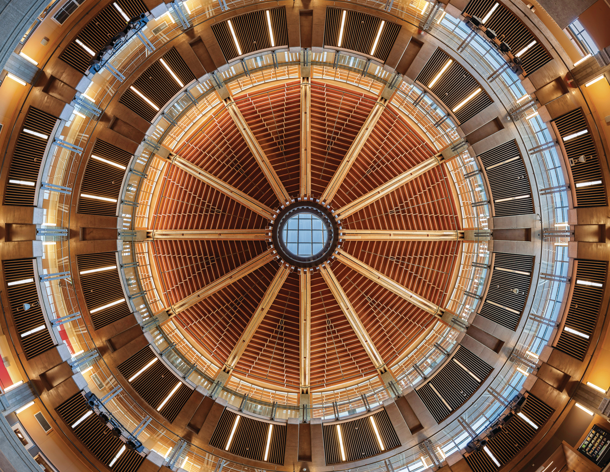 胶合层压木材(胶合木)、镶板、胶合板和实心锯厚木材组合在一起，创造出同心圆，如图所示，这是阿伯茨福德高中天花板向上的内部图像