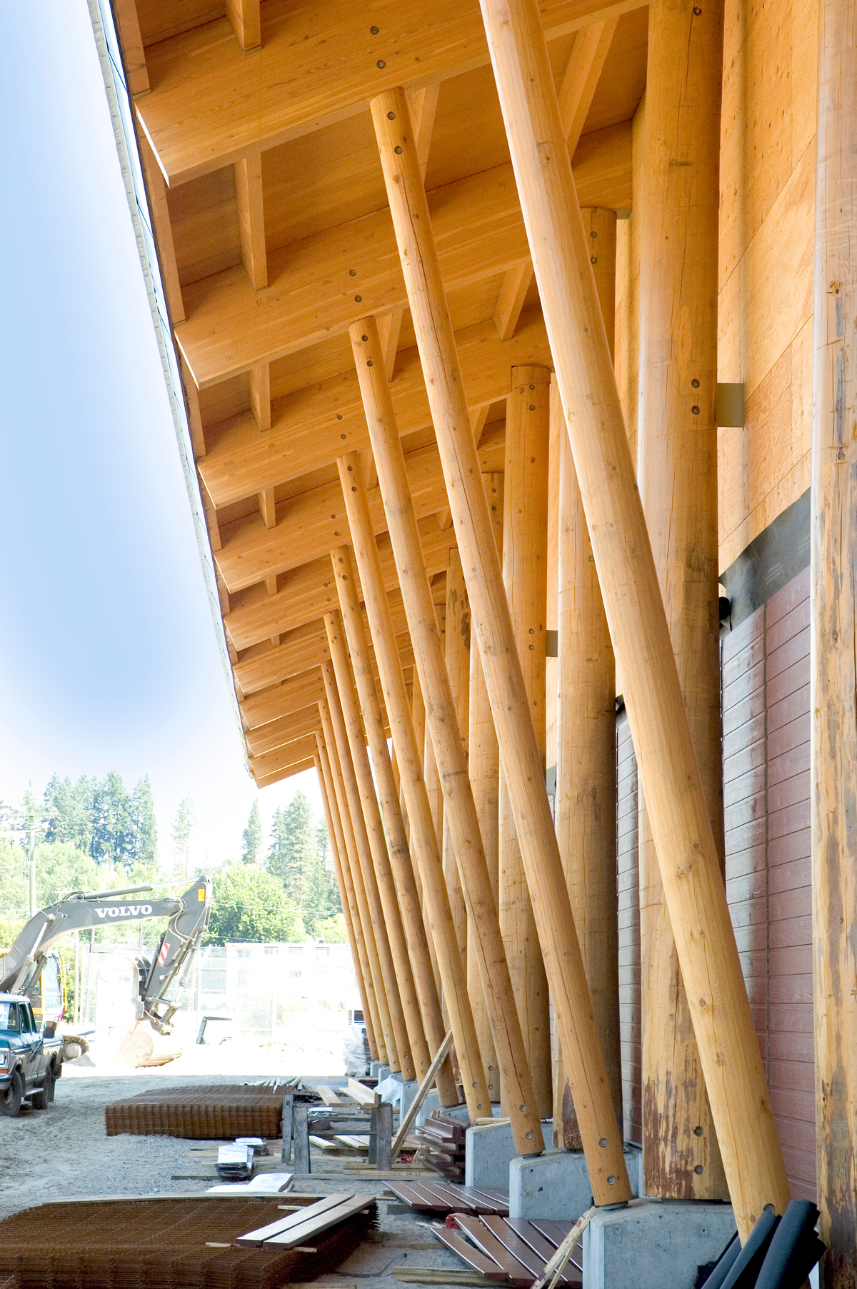 Armstrong-Spallumcheen竞技场活跃建筑的日间外部视图，显示胶合木水平屋面梁和道格拉斯杉木护套的垂直柱子+梁支撑
