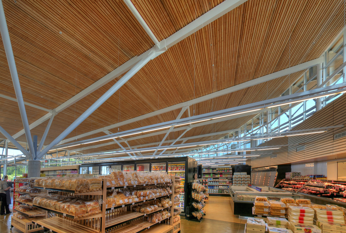 Askews Uptown Market的室内白天向上视图，具有3000平方米的浮动钉层压木材(NLT)屋顶结构和混合钢桁架工作