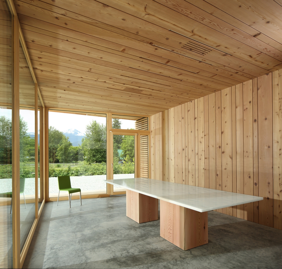 BC被动式房屋工厂会议室的室内下午视图，显示木质墙板和木质天花板镶板，向外延伸的大型玻璃