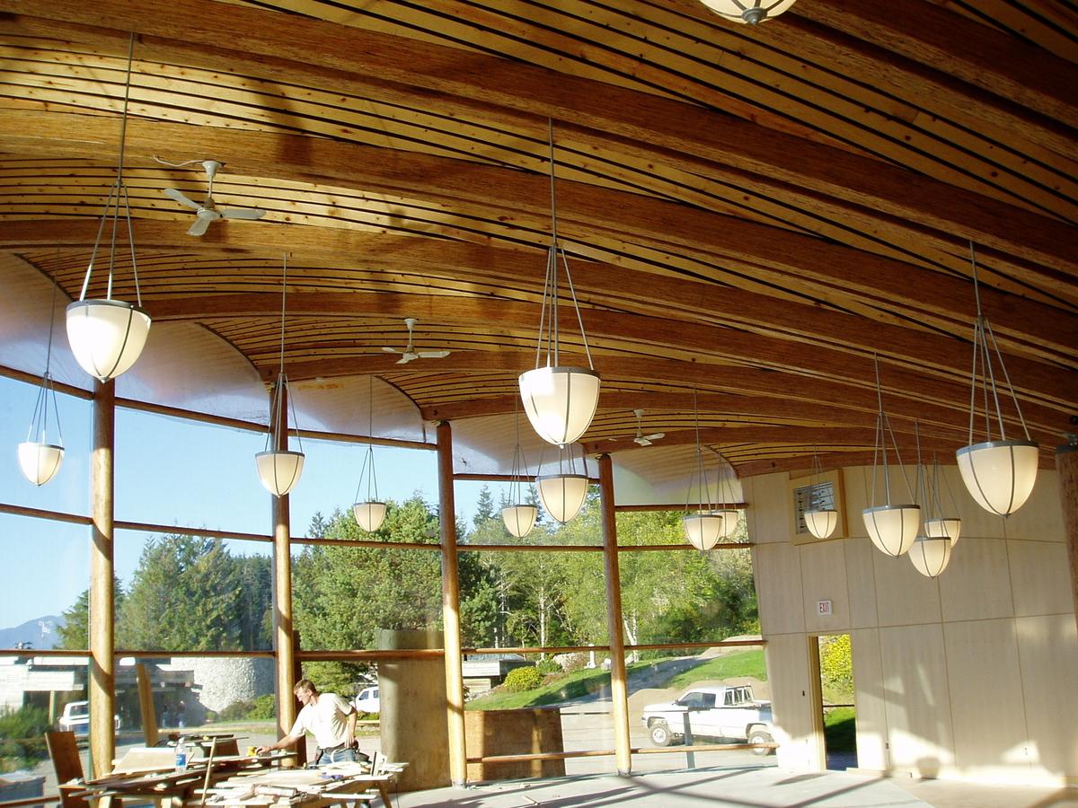 班菲尔德海洋中心中心房间的室内白天景观，透过宽阔的弯曲玻璃，上方是扇贝壳形的木质屋顶