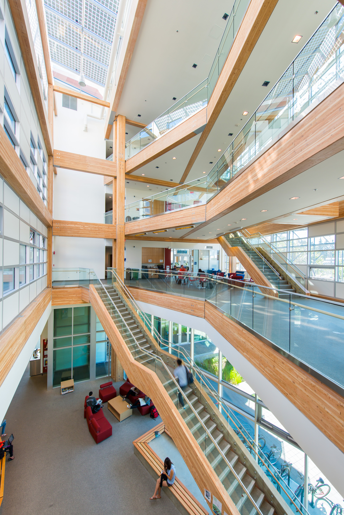 UBC可持续发展互动研究中心(CIRS)的室内充满活力的日间图像，玻璃正面的主中庭，显示多层楼梯，阳台和柱子，所有使用胶合木结构构件