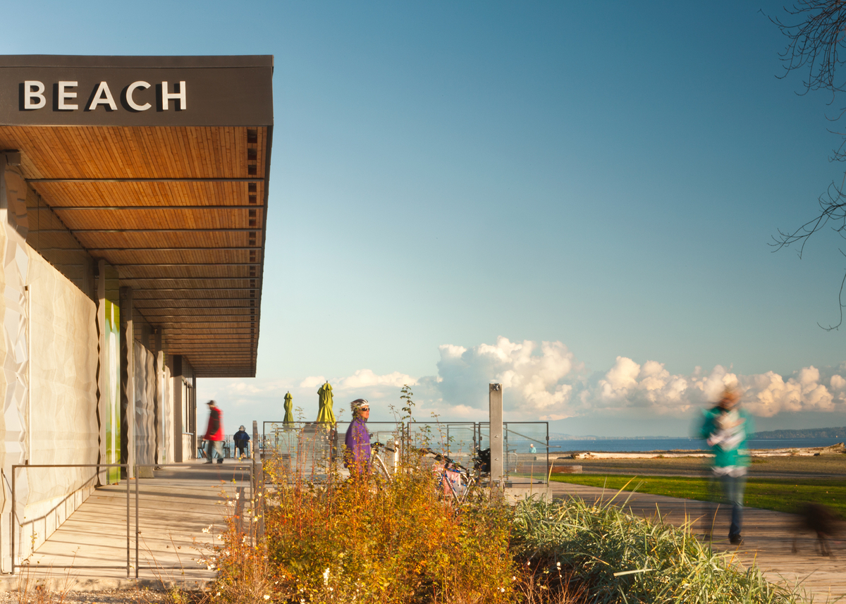 百周年海滩公园亭子阳光明媚的日间景观，展示游客享受悬挑天井屋顶的宽敞木拱