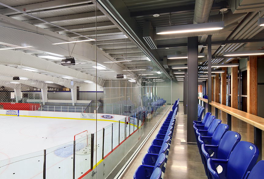 d'Cowichan湖体育场馆的内部视图，显示冰球溜冰场，蓝色座椅，以胶合木(胶合木)梁实木甲板和西部红雪松包层为特色
