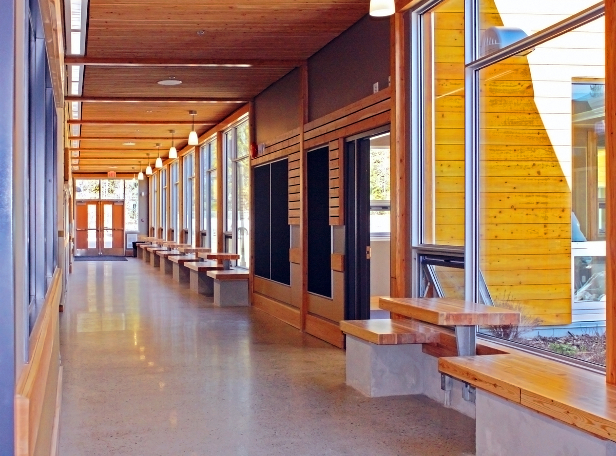 低层克劳福德湾小学-中学主走廊的内部视图，展示了混合结构，使用嵌板、柱子+梁和堆叠木板的屋顶