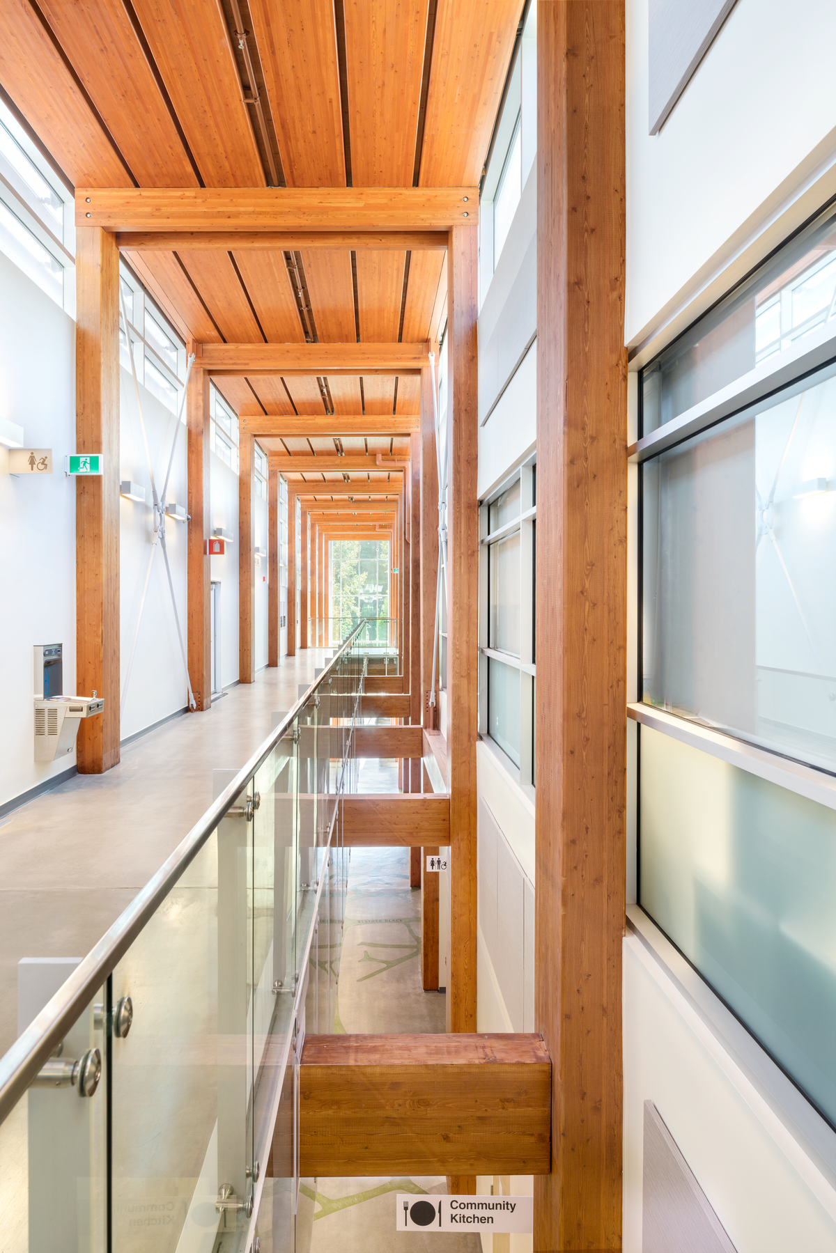 从顶层俯瞰德尔布鲁克社区康乐中心多层主走廊的室内景观，展示了由胶合木梁和柱支撑的美学木板