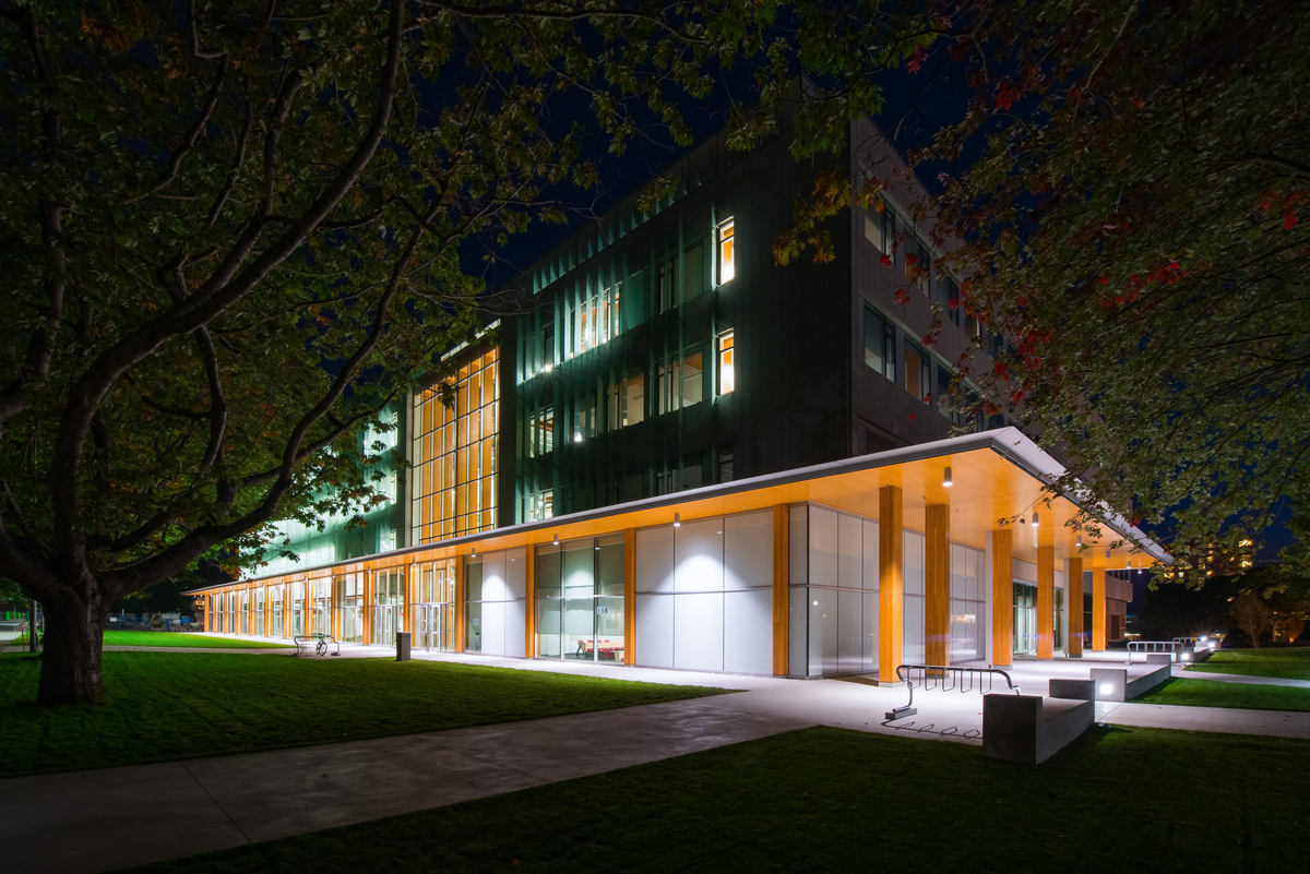 UBC校区中低层被动式房屋/高性能地球科学大楼的外部夜景，展示了胶合层压木材(胶合木)柱的周长，支撑着交叉层压木材(CLT)的拱腹