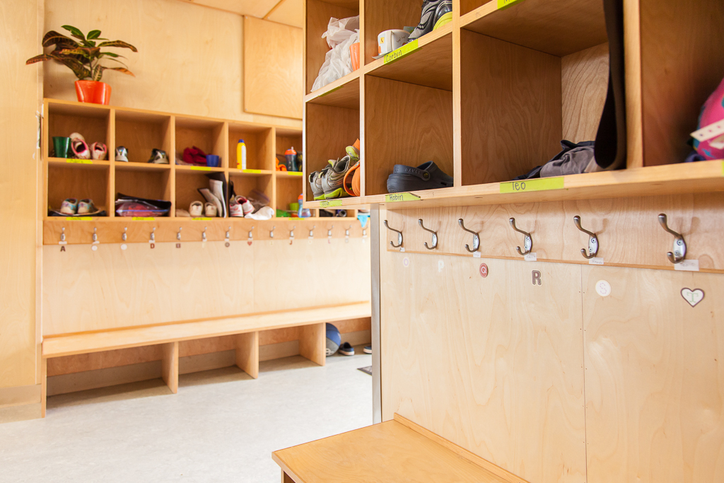 全日幼儿园教室储藏室的内部视图显示木镶板，木隔间，和外套挂钩