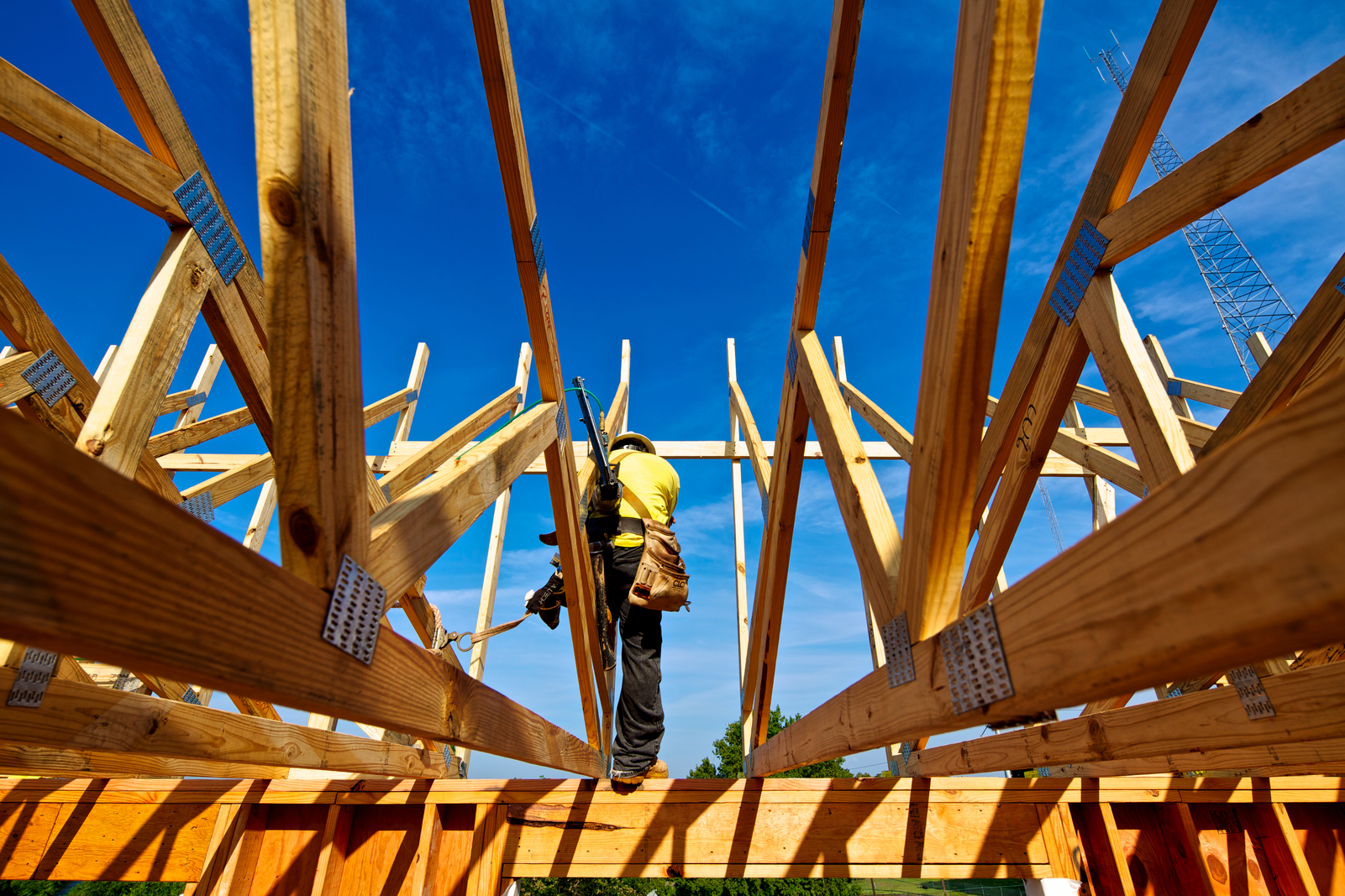 图为建筑工人用钉枪和防坠装置在低层住宅结构上安装的轻型结构梁和屋顶桁架