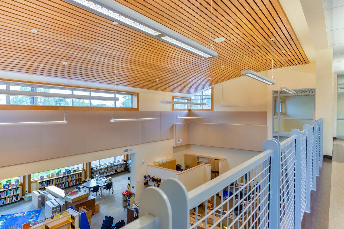 从二楼阳台可以看到J.W. Sexsmith小学图书馆低层的室内白天景观，展示了图书馆和其他噪音敏感区域使用的木条隔音天花板