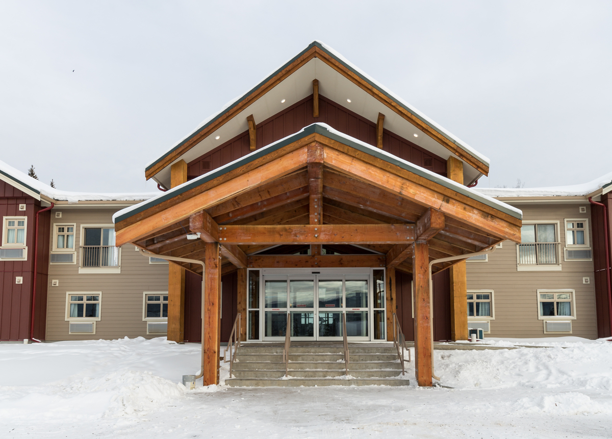 Key-oh Lodge的室外雪景，显示分层主入口和有盖楼梯，由木材、实锯重木材和桁架建造