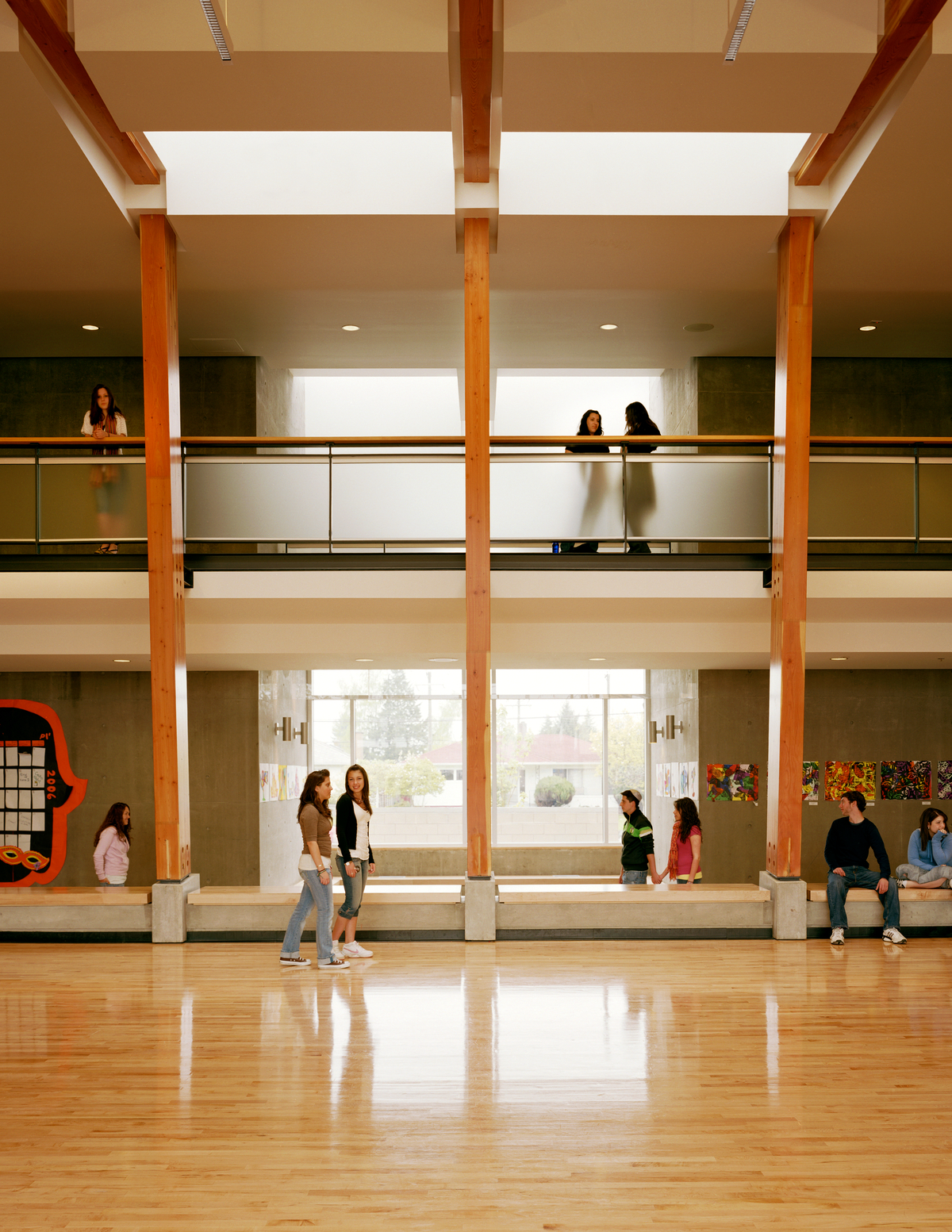 大卫王高中的室内白天视图，展示了中央多功能避难所内的学生，木地板和暴露的胶合层压木材(胶合木)横梁和柱子