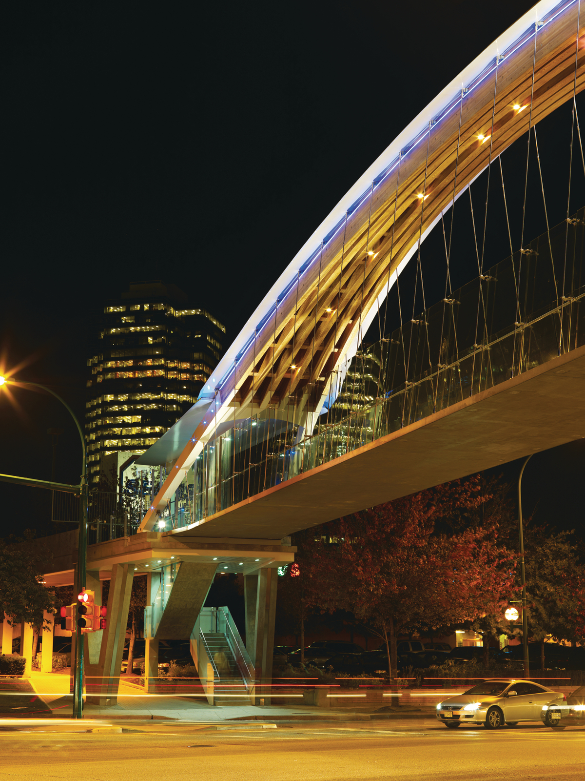 金斯威行人桥的夜间外观，显示双曲胶合木(胶合木)拱门，下面由钢索悬挂的人行道