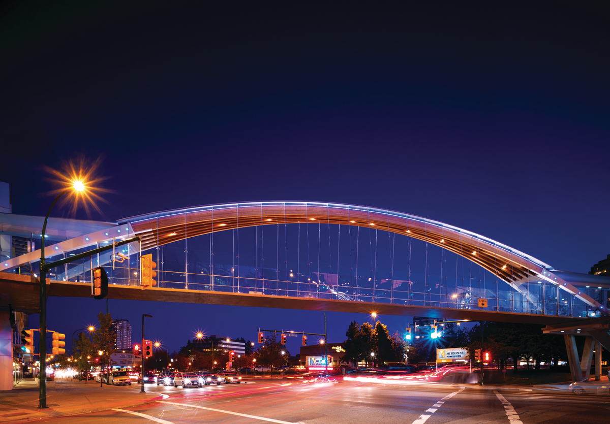 金斯威行人桥的外部夜景显示双曲胶合木(胶合木)拱门和下面由钢索悬挂的人行道