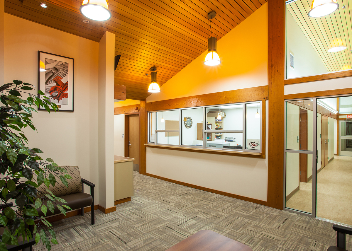 Kitsumkalum健康中心低层建筑的日间室内景观，大量使用木质装饰和装饰，包括木质天花板和镶板