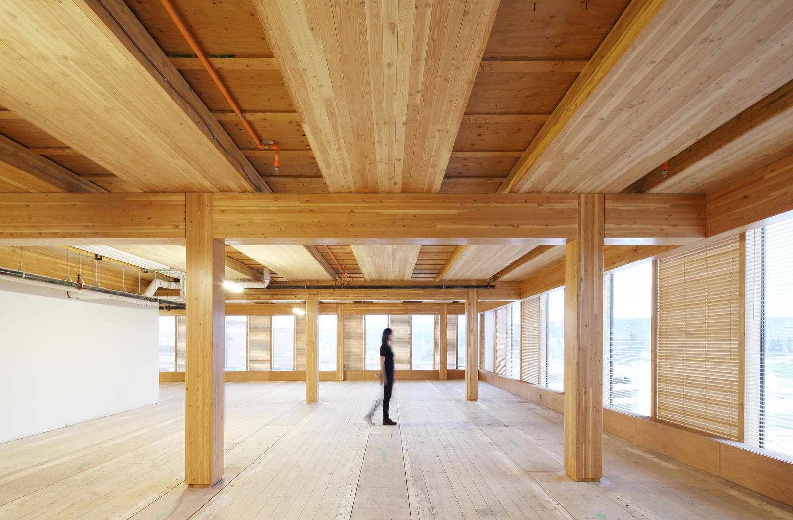 室内昼景，妇女行走在多层木结构中，显示木材的广泛使用，包括胶合木梁和柱支撑胶合板下层地板和下层硬木地板gydF4y2Ba