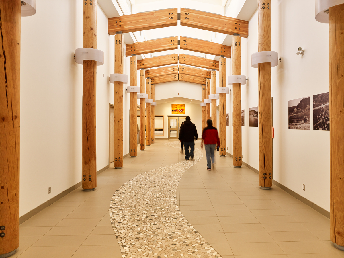 Nadleh Whutenne Yah行政和文化大楼中央走廊的室内日间视图，显示胶合木(胶合木)梁上方和木杆柱