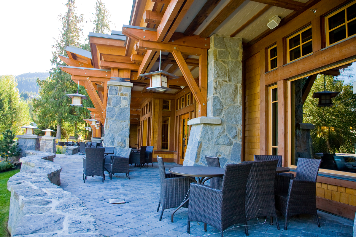 Nita Lake Lodge外部岩石和木材建造的走道和座位区域的外部白天视图，显示了木材的广泛使用，包括木制品，胶合板，实锯重木材，柱子+梁