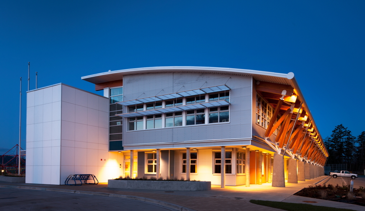 北萨尼奇中学的外部夜景，展示了混合金属、木材和混凝土结构，包括实心块木镶板、柱+梁和胶合木(胶合木)