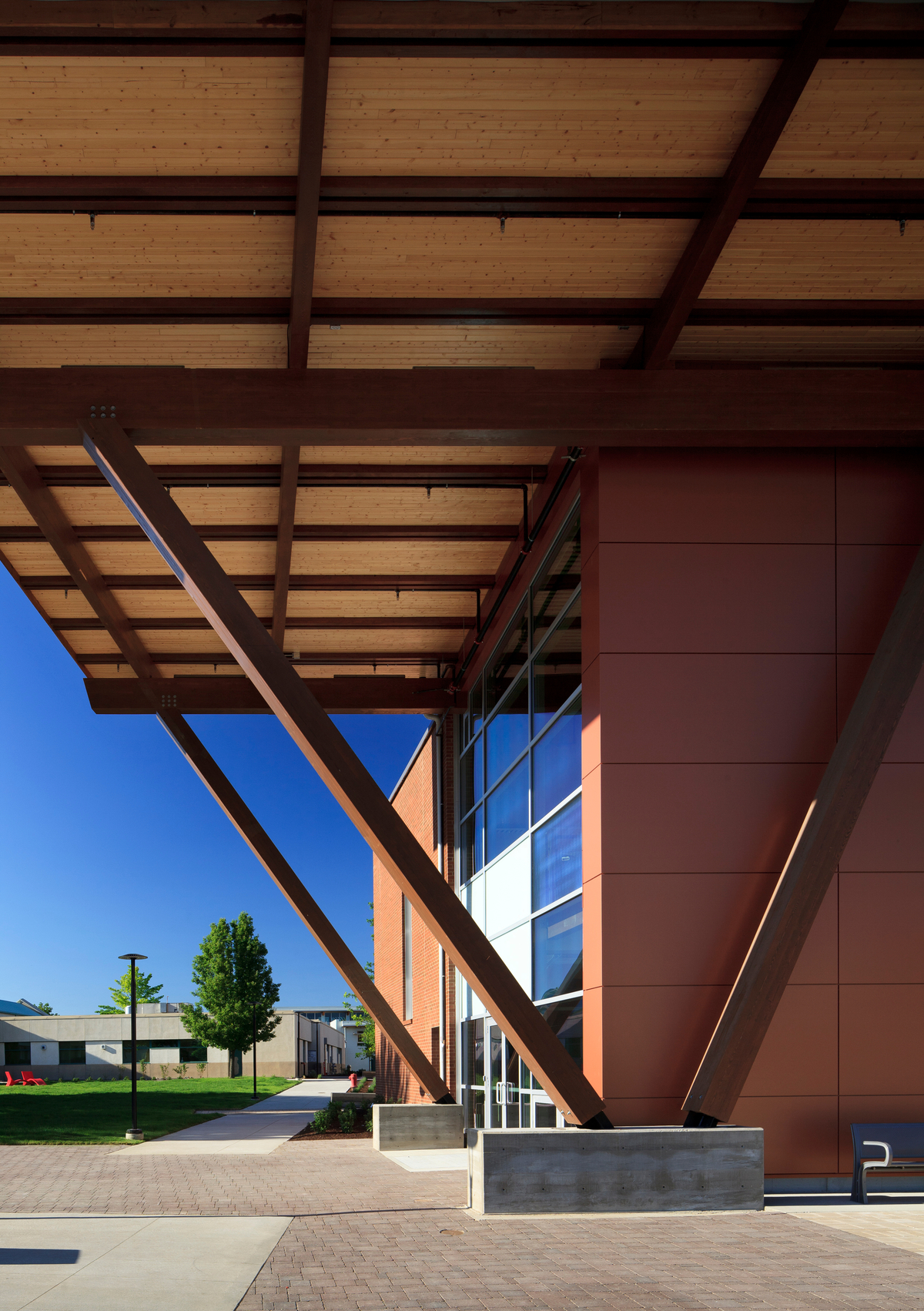 奥卡那根学院Jim Pattison卓越中心低层建筑的外部夜景，展示了由胶合木和金属混合结构组成的大型悬垂入口屋顶