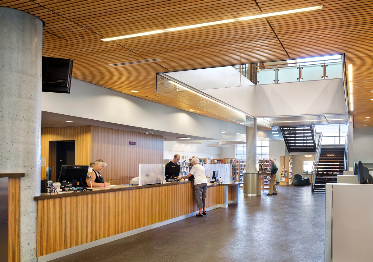 奥卡那根地区图书馆中心区域的日间室内景观显示板条木天花板，减少了环境噪音和木制品和贴面，增加了空间的丰富和温暖