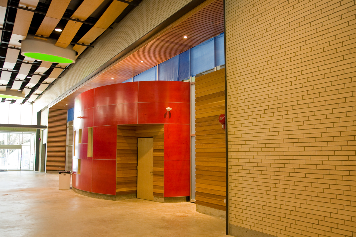 低层的Hillcrest中心主入口走廊的日间室内图像显示了木材的广泛使用，包括裸露的起伏的木板天花板