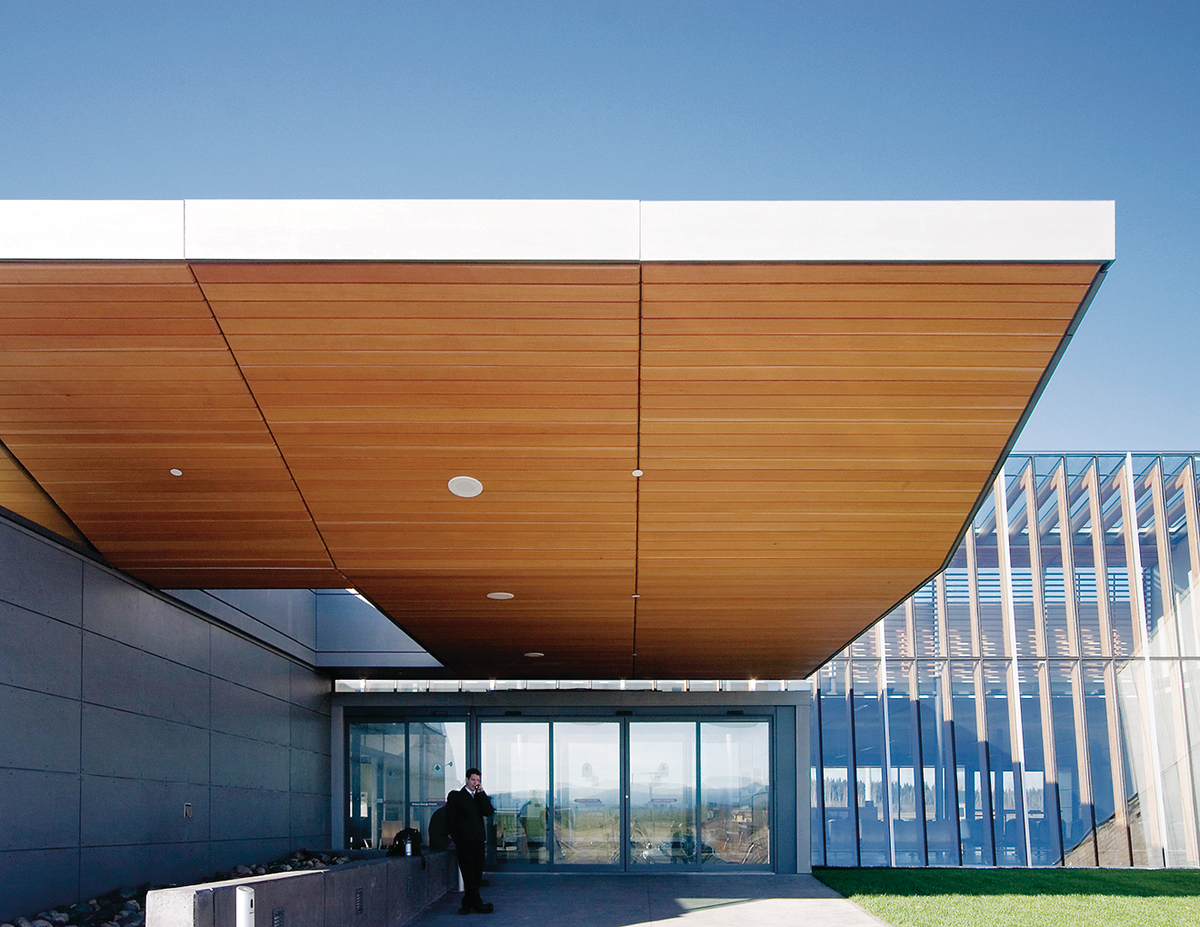 胶合层压木材(胶合板)和装饰性胶合板天花板镶板为乔治王子机场扩建入口屋顶的白天外部视图带来了结构和温暖