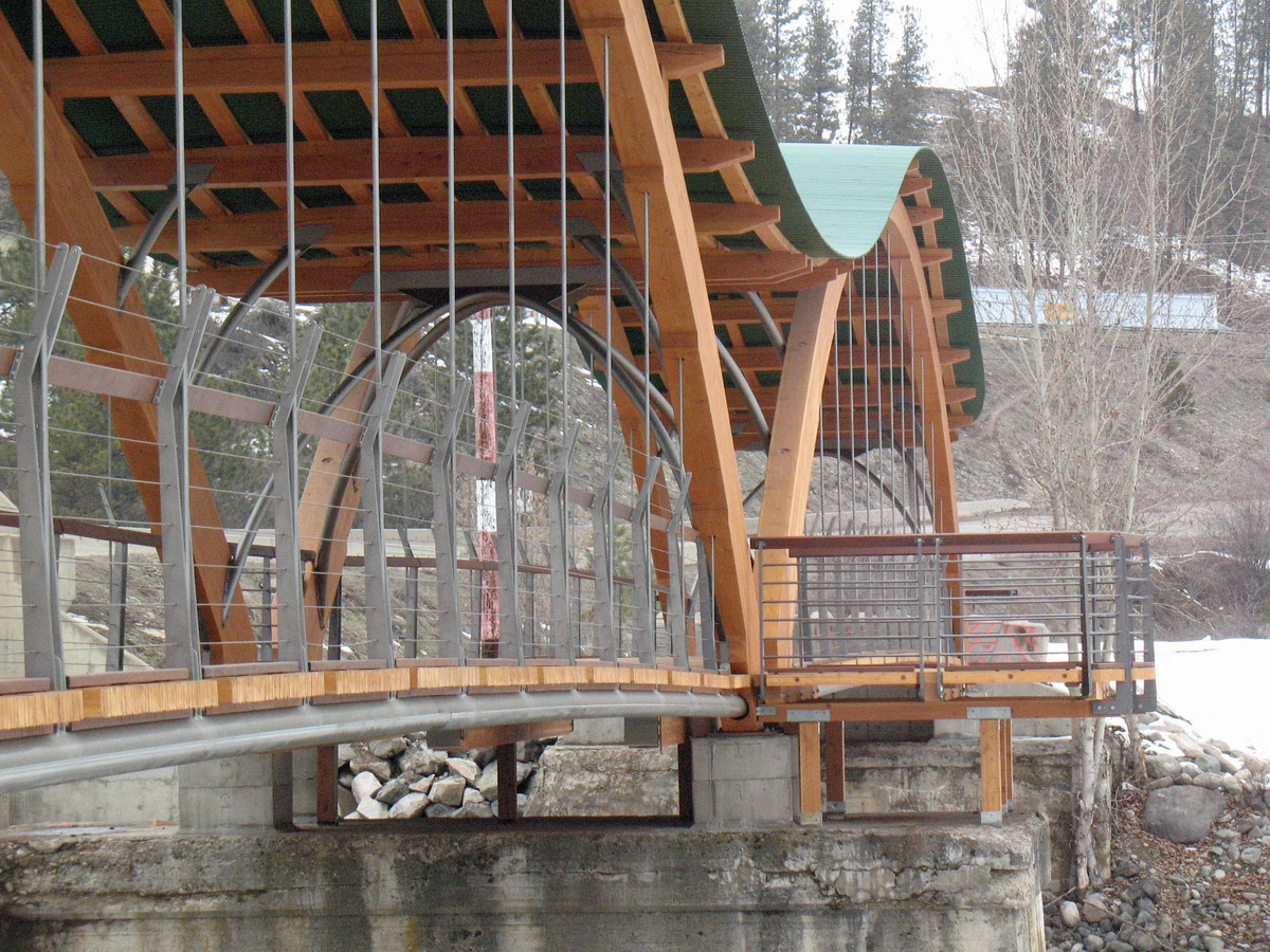 普林斯顿梦之桥的户外阴雪全景，突出悬挂的钢杆和甲板下的管状梁，显示大型胶合木(胶合木)拱门，木质甲板，和起伏的木材和钢鞘屋顶