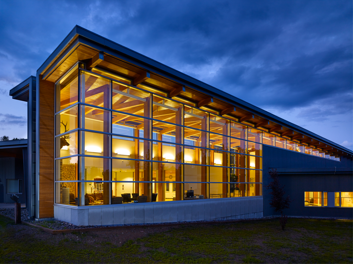 窗外的夜景望向先知河综合大楼广阔的玻璃空间，展示道格拉斯杉木胶合木(胶合木)柱梁系统，构成了这个大型线性大厅的主要结构