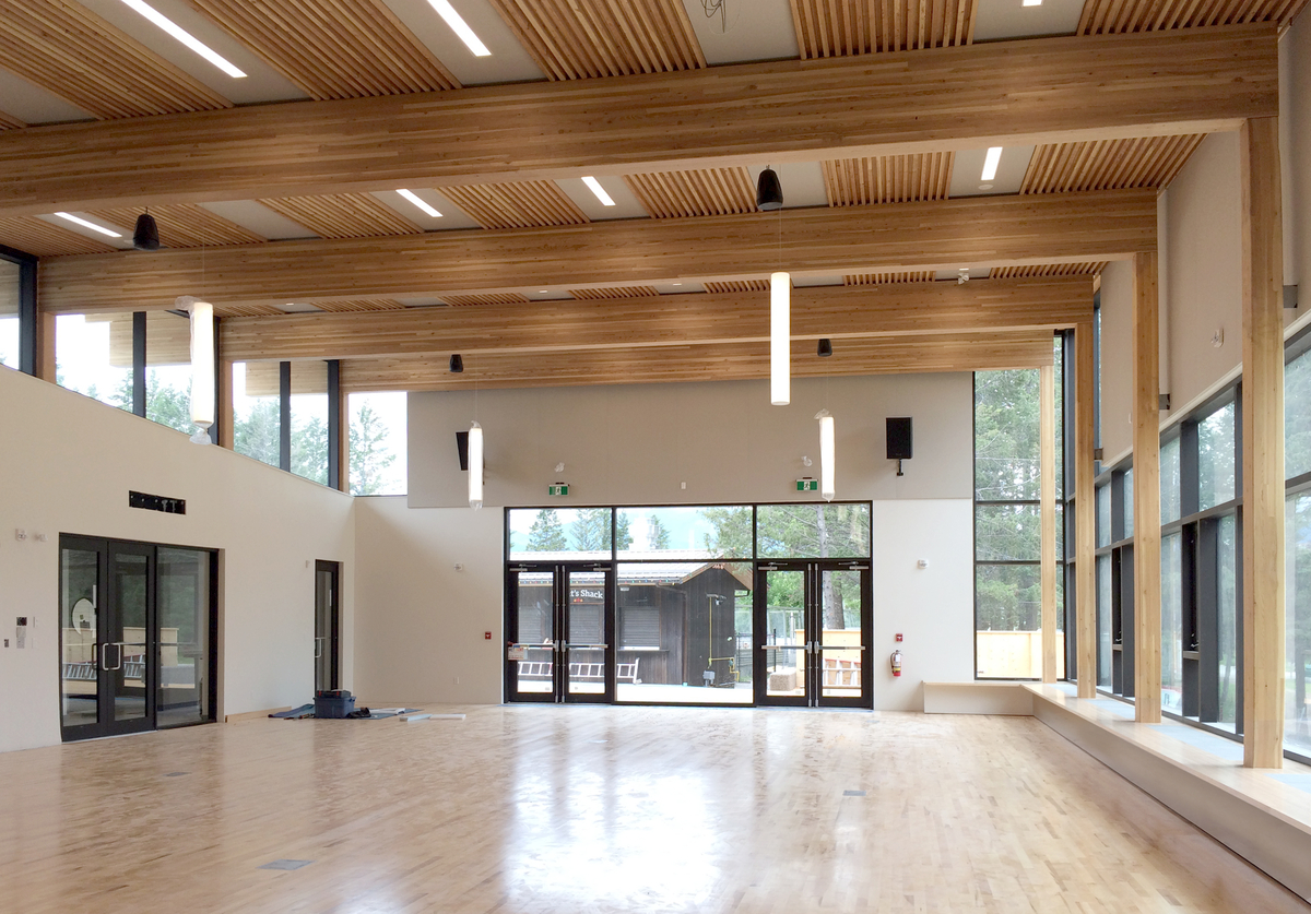 镭温泉社区大厅和图书馆的室内白天视图，显示胶合层压(胶合层)木材豆支撑榫板层压木材(DLT)屋顶部分