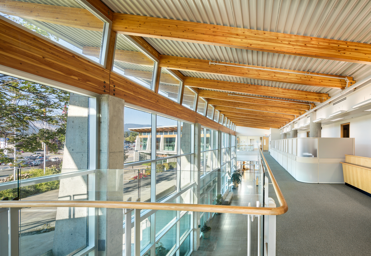 Salmon Arm法院和市政大厅的顶层阳台白天阳光充足，展示了大量的木材元素，包括胶合木、木制品、镶板、壁板和柱子+梁