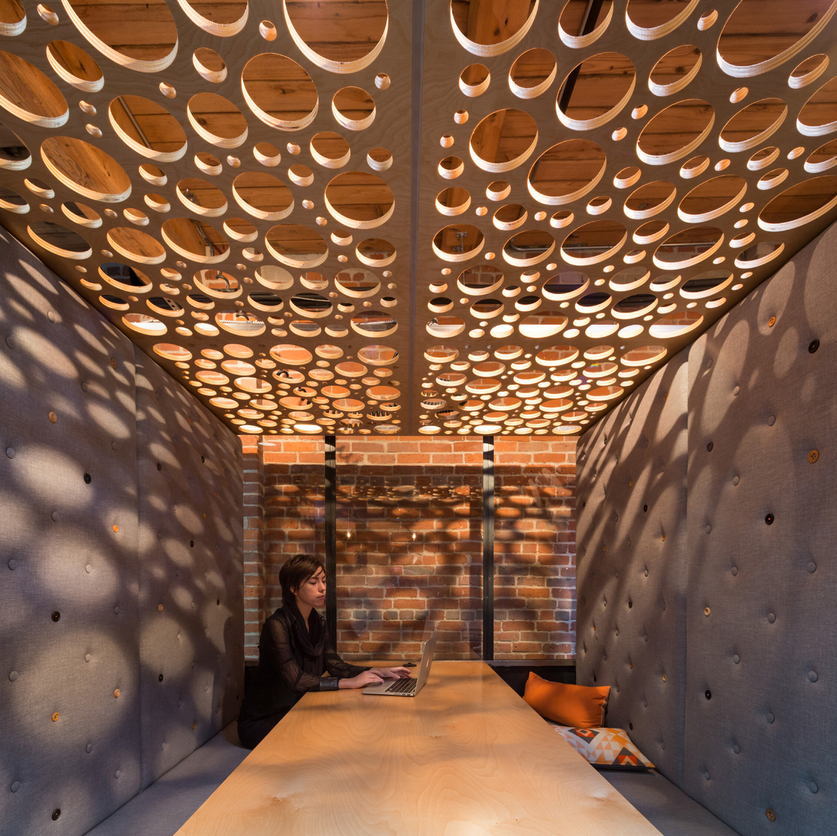 Slack总部的日间内部视图，显示了有百年历史的木材柱和梁结构，在胶合板假天花板上有无数的孔