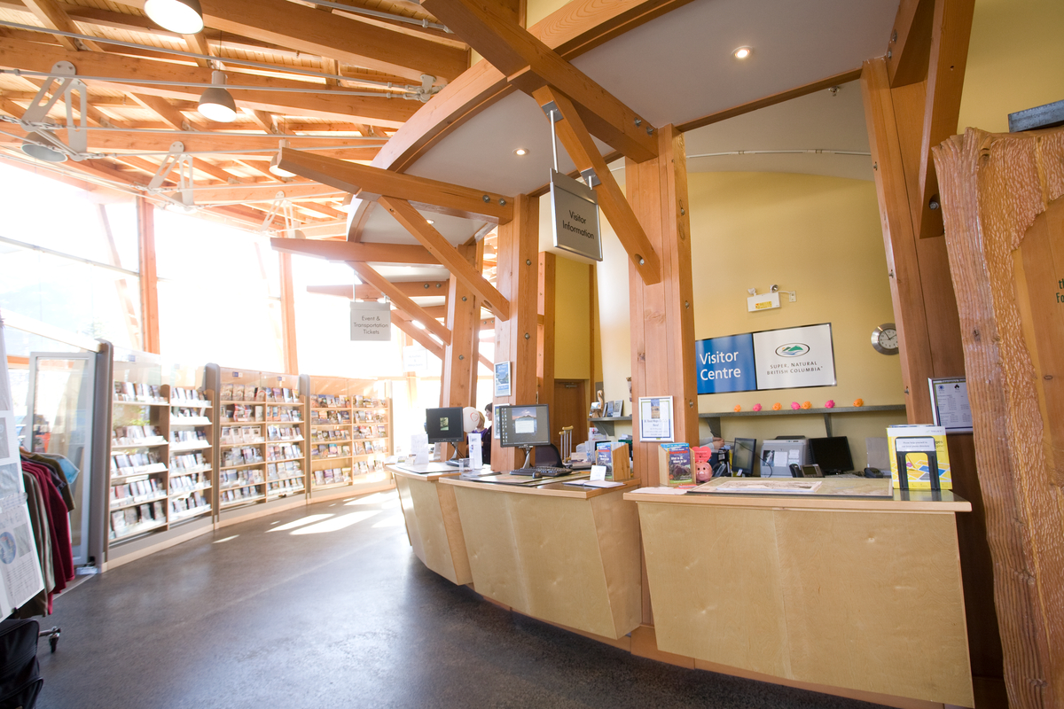 Squamish冒险中心礼品店的内部视图，显示实锯重木梁的屋顶，支撑木桁架和尺寸木材屋顶板条;所有以上的玻璃外墙和明亮的B2C显示器
