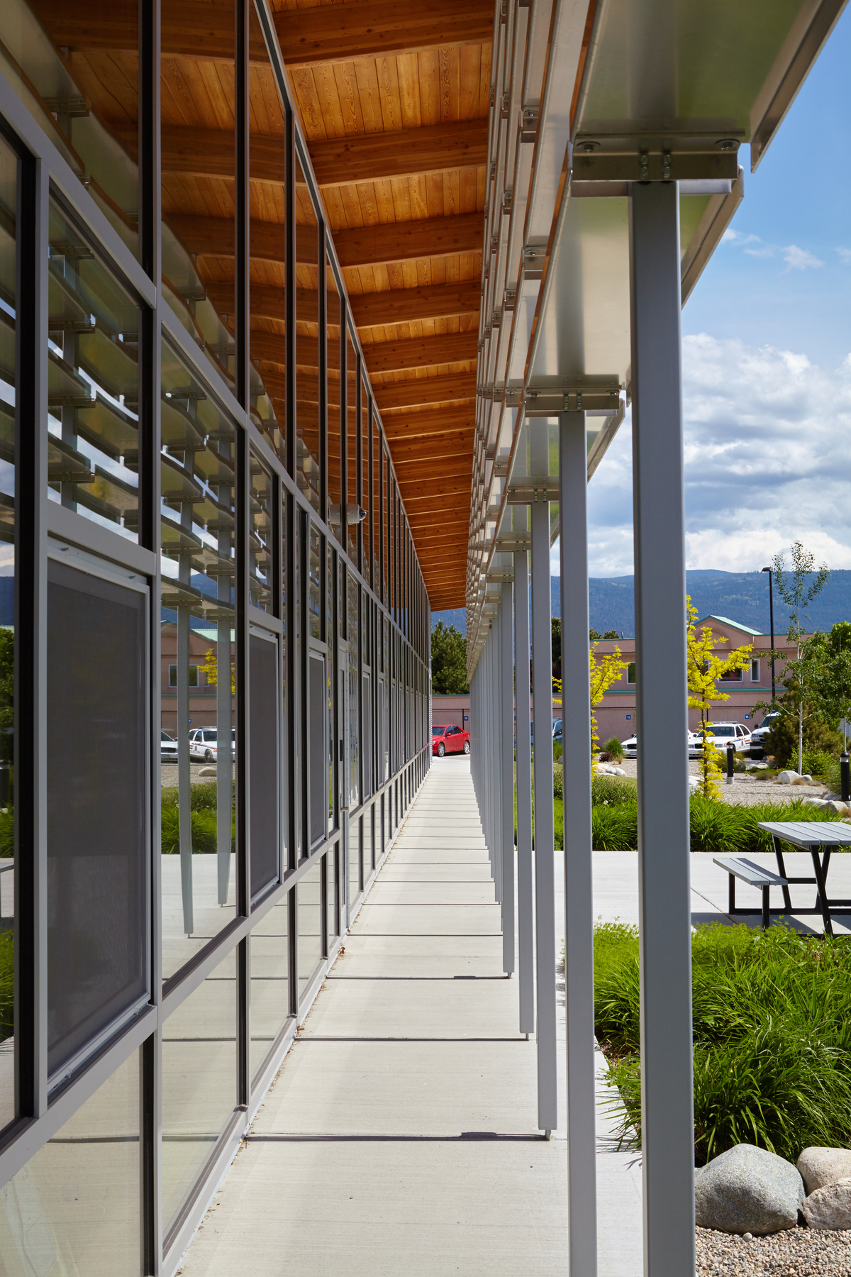 Summerland RCMP支队的日间外部景观，突出胶合木(胶合木)梁支撑外部拱腹，覆盖着未完工的松木板