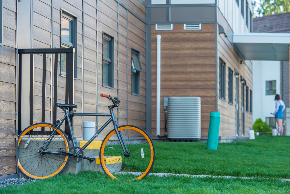 西三一大学雅各布森大厅白天的外部视图显示木墙板，窗户，绿色的草，和一辆橙色轮子的自行车