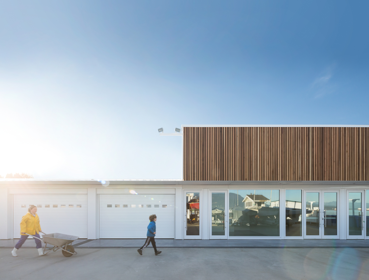 阳光明媚的白天，温哥华皇家游艇俱乐部码头建筑的外部图像，它结合了胶合层压木材(胶合木)、尺寸木材和胶合板，创造了一个功能存储和车间设施