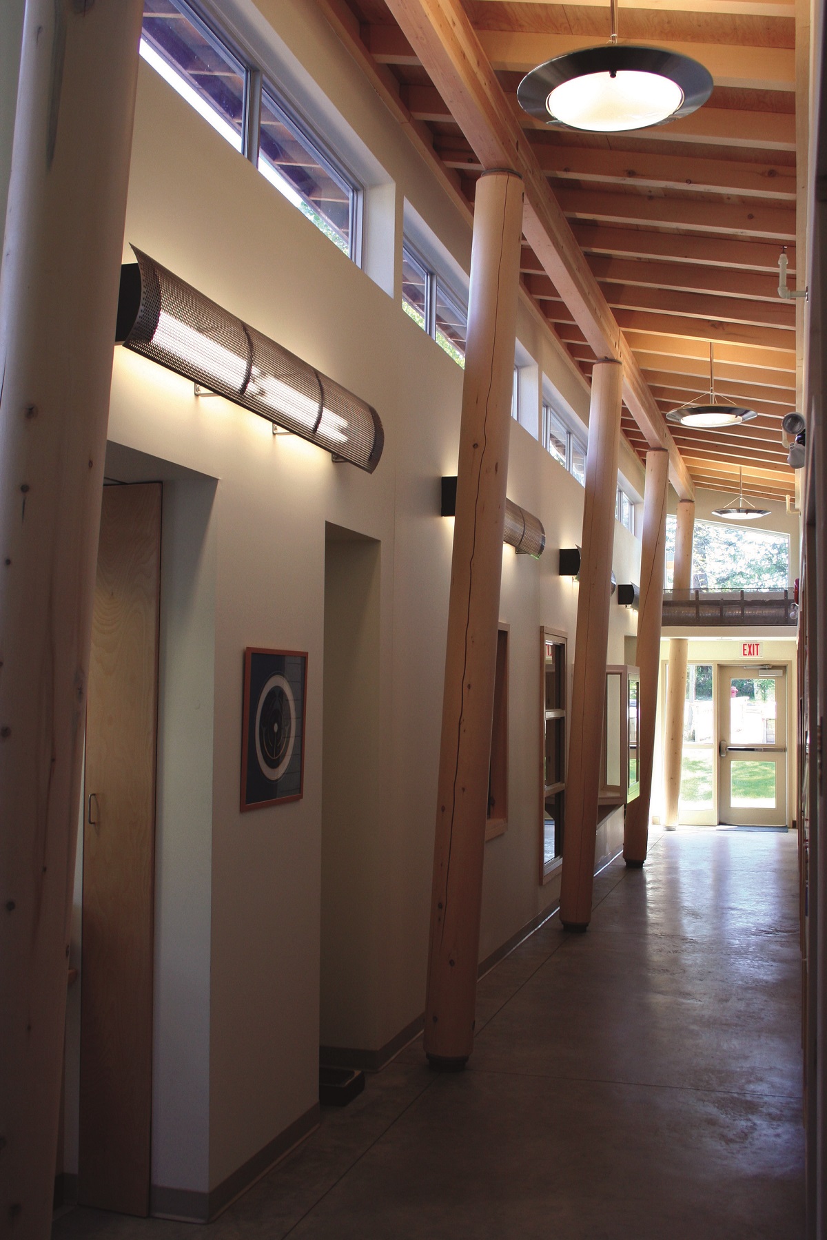 Takamine社区卫生服务大楼的内部走廊视图展示了实锯的重型木杆柱、梁和顶部有胶合板护套的屋顶桁架