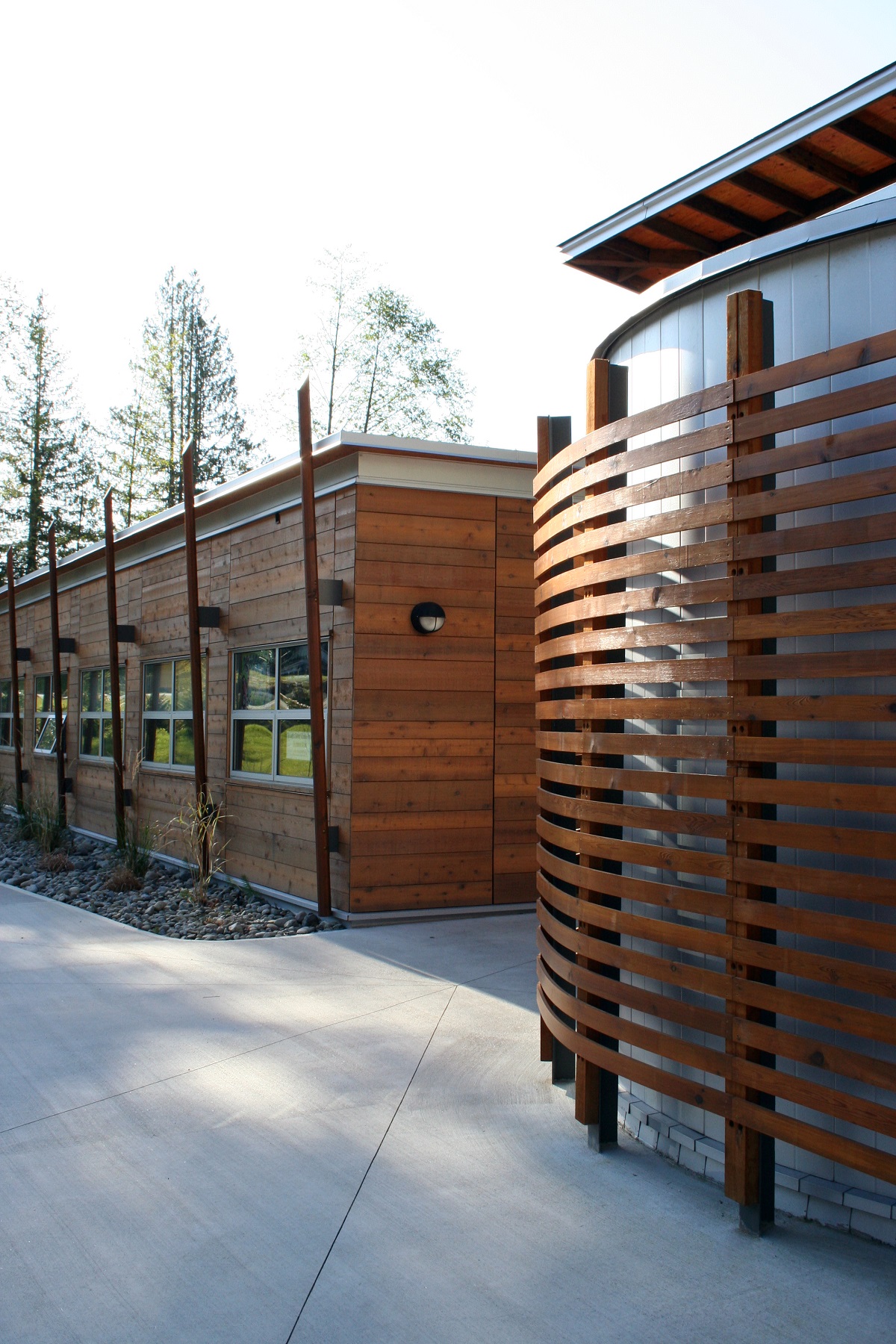 Tla'Amin社区卫生服务大楼低矮的外景下午视图，显示大量使用木壁板和装饰木装饰