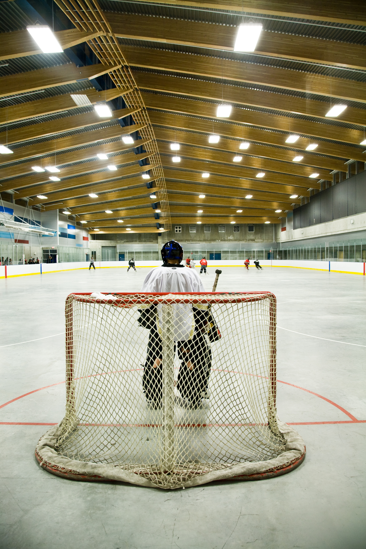 特劳特湖溜冰场的内部视图，从守门员的角度展示冰球练习，所有都在胶合木(胶合木)屋顶设计下，提供自然通风和照明