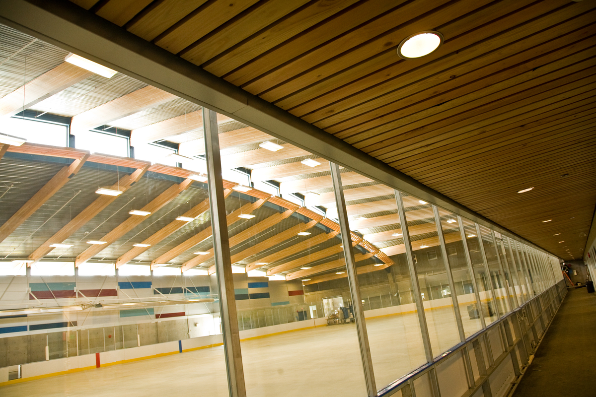 特劳特湖溜冰场白天的室内景观，走廊玻璃，空间木材板条天花板，可以看到胶合木(胶合木)屋顶梁的溜冰场