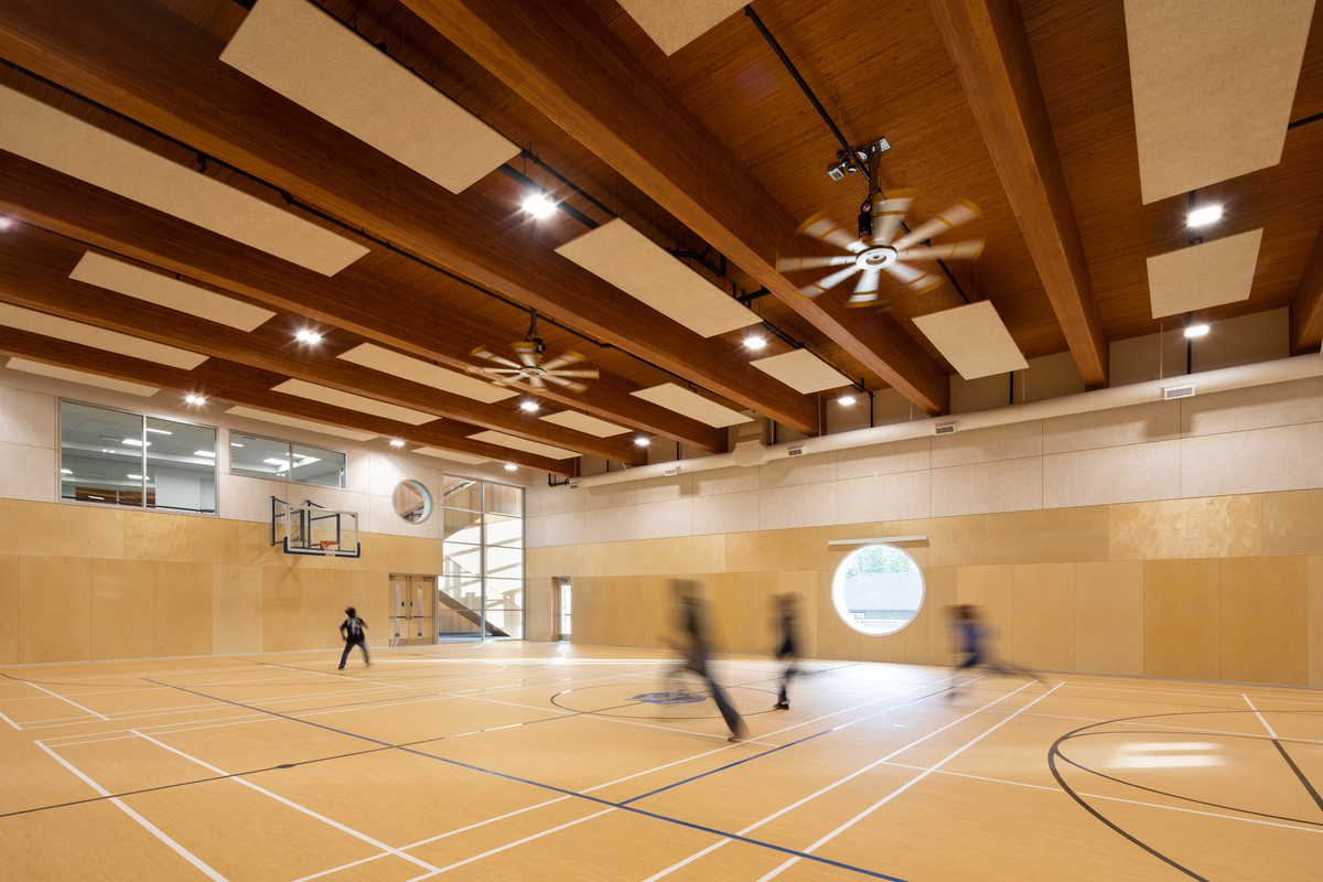 Ts 'kw 'aylaxw文化和社区卫生中心体育馆的内部视图，展示胶合层压木材(胶合木)和钉层压木材(NLT)在一场临时篮球比赛中。