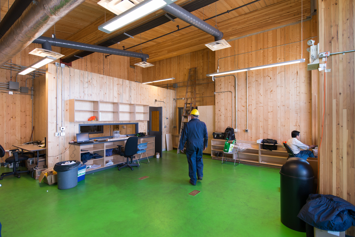 UBC生物能源研究和演示设施低层木材的室内日间景观，展示了工作人员在交叉层压木材(CLT)镶墙围成的房间中，天花板由大型胶合层压木材(胶合木)梁支撑