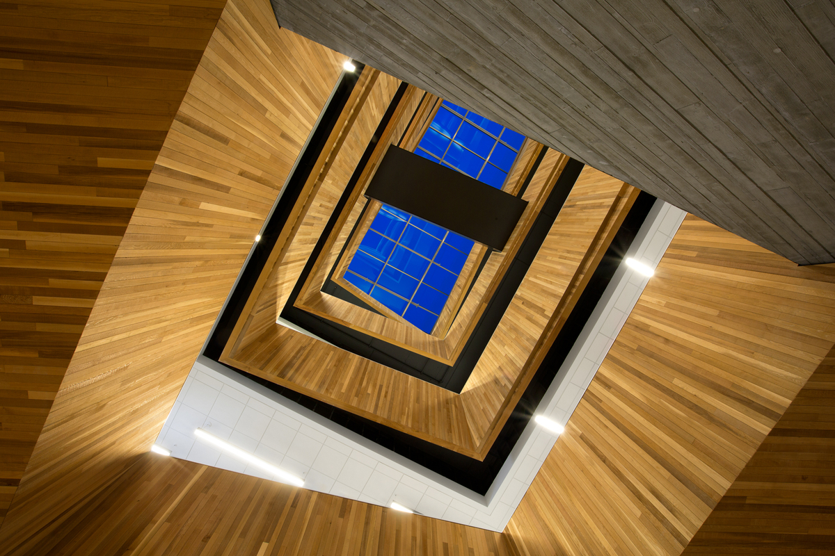 多层向上的楼梯井内部图像显示整个建筑突出使用了裸露的木材，包括中庭的墙覆层，裸露的墙防护和装饰