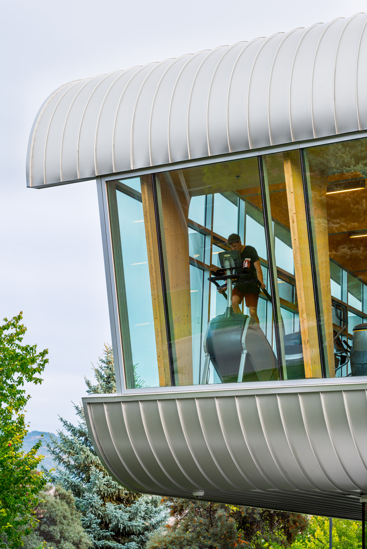 混合两层的UBCO健身和健康中心的日间外观，展示了混合金属和玻璃外观，内部有交叉层压木材(CLT)和胶合层压木材(胶合木)元素