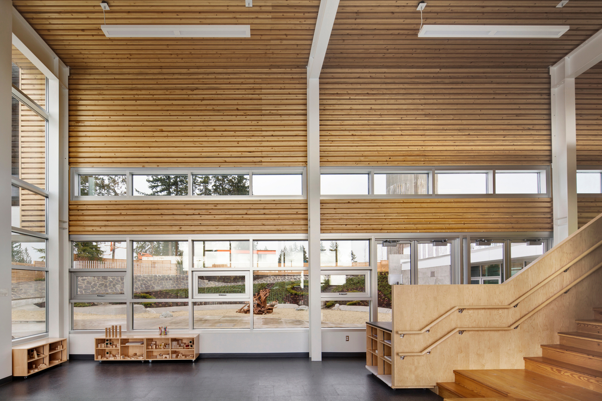 墙壁和天花板的钉层压木材(NLT)面板由受山松甲虫侵扰影响的回收木材制成，创造了波纹表面，增加了视觉乐趣，并改善了繁忙的大学城托儿中心活动空间的声学效果